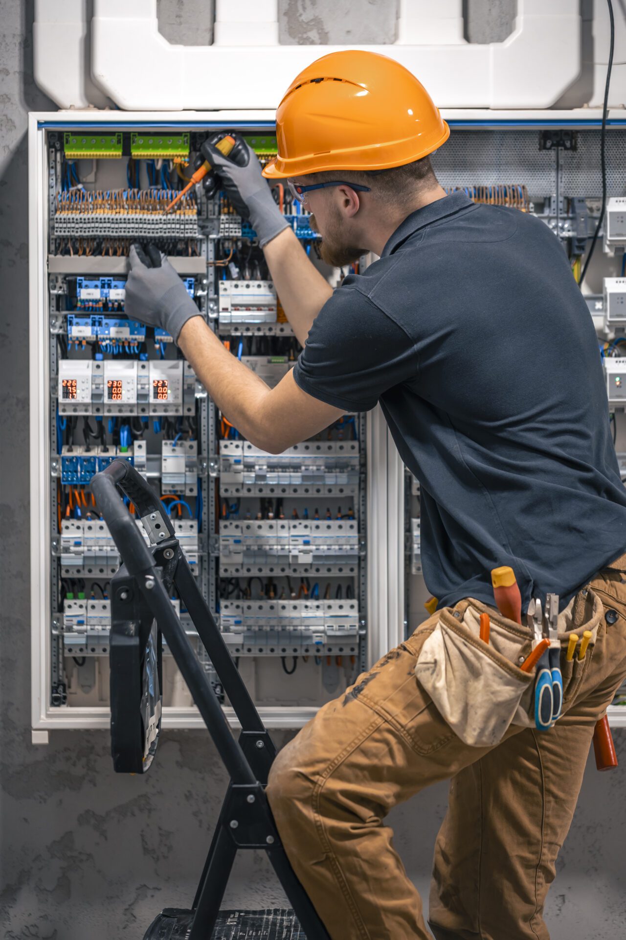 Male electrician working in a switchboard with fuses.